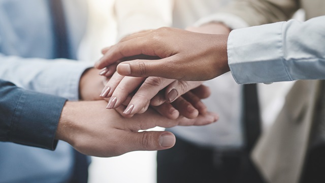 Workers demonstrating teamwork with hand gesture.